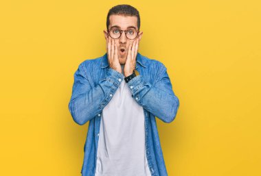 Gündelik kıyafetler giyen genç beyaz adam korkmuş ve şok olmuş, şaşırmış ve şaşkın bir yüz ifadesi var. 