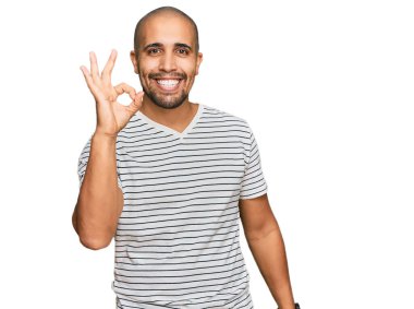 Normal kıyafetler giyen İspanyol bir adam gülümsüyor. El ve parmaklarıyla 