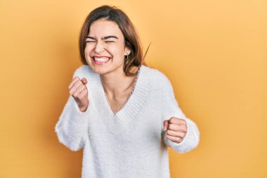 Başarı için heyecanlı, kolları havada, gözleri kapalı, sıradan kıyafetler giyen genç beyaz kız zaferi kutluyor. Kazanan konsept. 