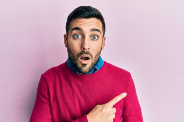 Gündelik giysiler giyen genç İspanyol adam parmaklarını yana doğru göstererek şaşırdı, ağzı açık hayret içinde kaldı.. 