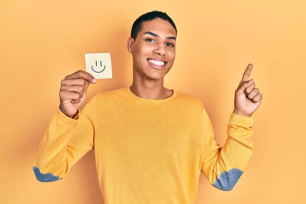 Joven Afroamericano Chico Sosteniendo Sonrisa Recordatorio Sonriendo Feliz Señalando Con — Foto de Stock