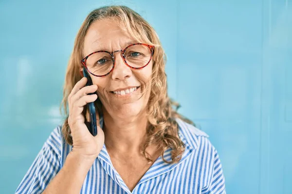 中世の白人女性は 市内のスマートフォンで幸せな話を笑っています — ストック写真