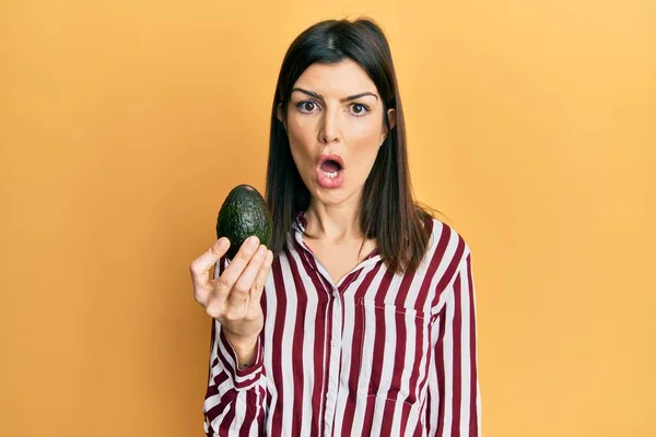 Young Hispanic Woman Holding Avocado Scared Amazed Open Mouth Surprise — Stock Photo, Image