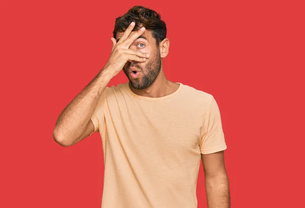 Pohledný Mladý Muž Vousy Nenucené Košili Vykukující Šoku Zakrývající Obličej — Stock fotografie