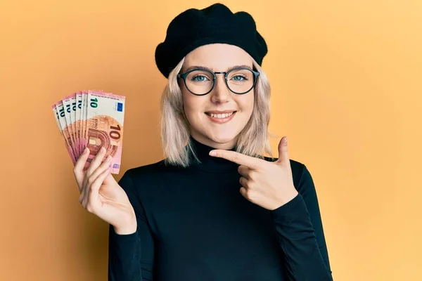 Mladá Blondýna Dívka Drží Eurobankovky Úsměvem Šťastný Ukazující Rukou Prstem — Stock fotografie