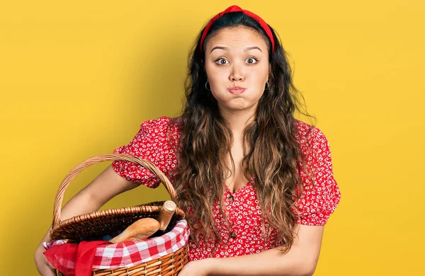 Junge Hispanische Mädchen Mit Picknick Weidenkorb Mit Brot Puffenden Wangen — Stockfoto