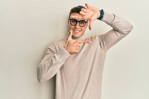 스페인 청년은 터틀넥 스웨터를 손가락으로 얼굴로 만드는 미소를 창의성 사진의 — 스톡 사진