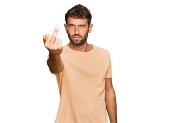 Handsome young man with beard wearing casual tshirt showing middle finger, impolite and rude fuck off expression 