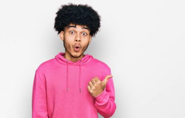 Afro saçlı, sıradan pembe kazaklı genç Afro-Amerikalı bir adam elini yana uzatıp, ağzını açtığında şaşkın bir ifadeyle şaşırdı.. 