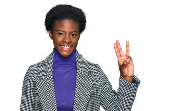 Genç Afro-Amerikan kızı, günlük kıyafetler giyip üç numaralı parmaklarıyla işaret ederken kendinden emin ve mutlu bir şekilde gülümsüyor.. 