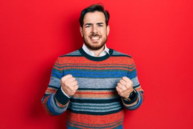 Sakallı, zarif yün kazak giyen, kolları havada, gözleri kapalı zaferi kutlayan yakışıklı beyaz adam. Kazanan konsept. 