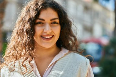 Genç İspanyol kadın gülümseyerek şehirde mutlu mesut dikiliyor..
