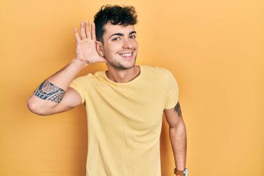 Gündelik tişört giyen, ağzı kulaklarında gülümseyen dedikoduları ve dedikoduları dinleyen genç bir İspanyol. Sağırlık kavramı. 