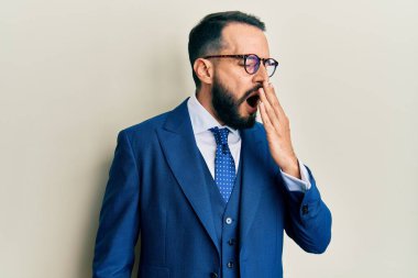 Sakallı, takım elbiseli ve kravatlı genç bir adam ağzıyla ağzını kapatmaktan sıkılmış. Huzursuz ve uykulu.. 