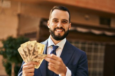 Genç işadamı gülümseyerek şehirde dolarları sayıyor..