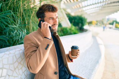 Zarif ceketli yakışıklı bir iş adamı. Açık havada akıllı telefon kullanıyor.