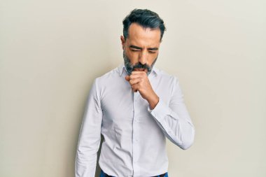 Sakallı ve gri saçlı orta yaşlı bir adam günlük beyaz gömlek giyiyor kendini iyi hissetmiyor ve soğuk algınlığı veya bronşitin belirtisi olarak öksürüyor. sağlık hizmeti kavramı. 