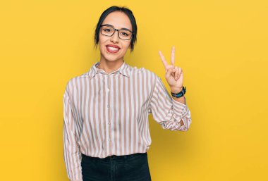 Gündelik kıyafetler ve gözlük takan genç İspanyol kız kameraya bakıp zafer işareti yapıyor. İki numara.. 