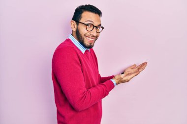 Sakallı, iş gömleği ve gözlüklü İspanyol bir adam. Avuç içleri açık, fotokopi alanını gösteriyor. Gülümseyen mutlu mutlu bir gülümseme. 