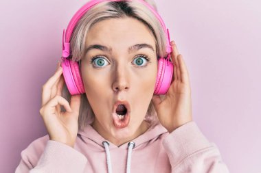 Kulaklıkla müzik dinleyen genç sarışın kız şaşkınlık ve şaşkınlık dolu bir ifade, korku ve heyecan dolu bir yüz ile şok olmuş ve korkmuştu.. 