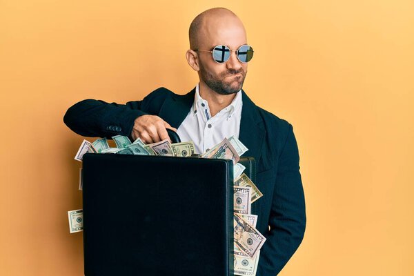 Молодой латиноамериканец держит портфель с долларами, улыбаясь, смотрит в сторону и думает:. 