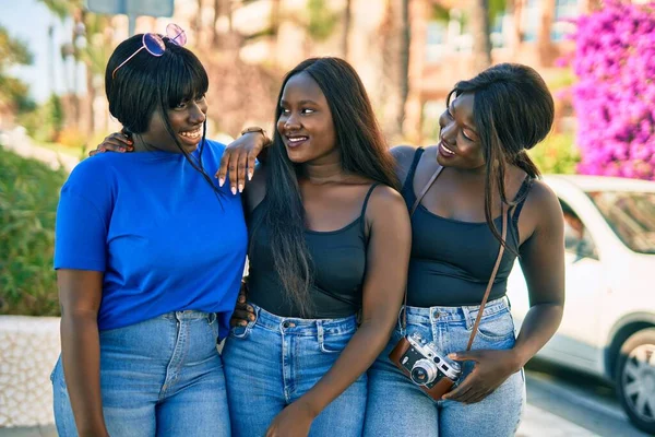 Three african american friends smiling happy hugging at the city.