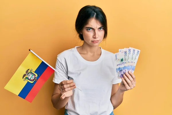 年轻的高加索女人拿着Colombia国旗和Colombian比索钞票 怀疑和紧张 因为问题皱着眉头 消极的人 — 图库照片