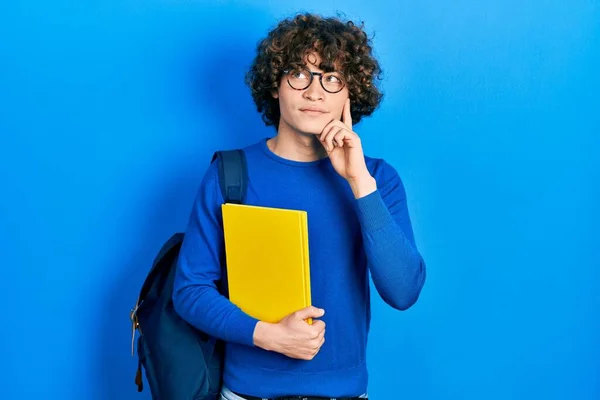 Bonito Jovem Vestindo Mochila Estudantil Segurando Livro Rosto Sério Pensando — Fotografia de Stock