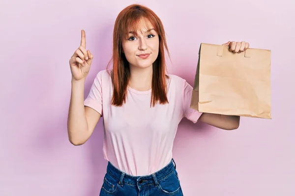 Pelirroja Mujer Joven Sosteniendo Llevar Bolsa Papel Sonriendo Con Una — Foto de Stock