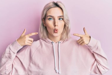 Genç sarışın kız parmaklarıyla ağzını işaret ederek balık suratlı ve şaşı gözlü, çılgın ve komik.. 