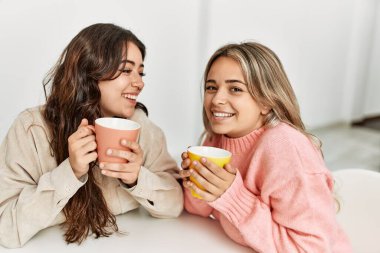 Genç ve güzel bir çift gülümseyerek evde kahve içiyor..