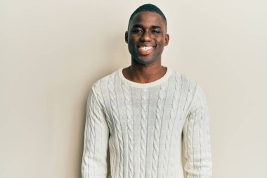 Yüzünde mutlu ve havalı bir gülümseme olan sıradan kıyafetler giyen genç Afro-Amerikan bir adam. şanslı kişi. 