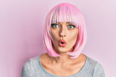 Pembe peruklu genç, beyaz bir kadın. Korkmuş ve ağzı açık kalmış, şaşırmış, inançsız bir yüz. 