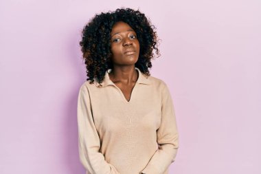 Sıradan kıyafetler giyen genç Afro-Amerikan kadın yüzünde ciddi bir ifadeyle rahatladı. Basit ve doğal bir şekilde kameraya bakıyorsun.. 