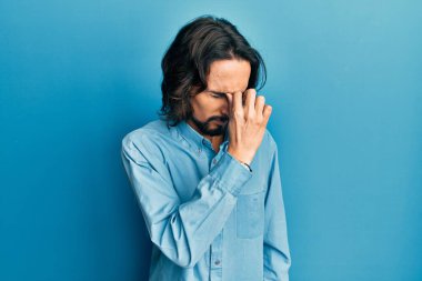 Günlük kıyafetler giyen genç İspanyol adam yorgun burnu ve gözleri ovuşturup yorgun ve baş ağrısı çekiyor. Stres ve hüsran kavramı. 