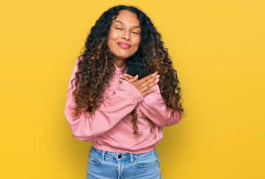 Kıvırcık saçlı, sıradan bir kazak giyen, elleri göğsünde, gözleri kapalı ve yüzünde minnet ifadesi olan İspanyol bir kadın. sağlık kavramı. 