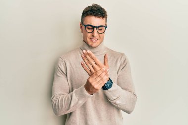 Balıkçı yaka kazak giyen İspanyol genç bir adam ellerinde ve parmaklarında ağrı ve iltihap var. 