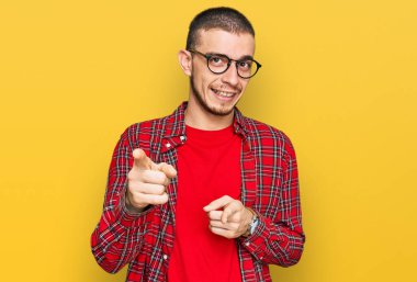 Gündelik kıyafetler giyen İspanyol genç adam mutlu ve komik yüzüyle kamerayı işaret ediyor. iyi enerji ve titreşimler. 