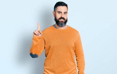 Kış süveteri giymiş sakallı İspanyol bir adam başarılı bir fikri işaret ediyor. Heyecanlı ve mutlu. Bir numara.. 