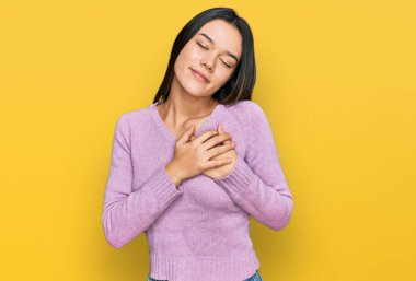 Gündelik kıyafetler giyen genç İspanyol kız elleri göğsünde, gözleri kapalı ve yüzünde minnet dolu bir jest ile gülümsüyor. sağlık kavramı. 