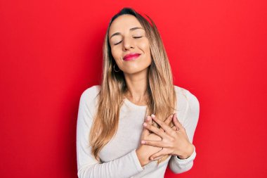 Güzel İspanyol kadın kırmızı diyadem giyiyor. Elleri göğsünde, gözleri kapalı gülümsüyor ve yüzünde minnet ifadesi var. sağlık kavramı. 