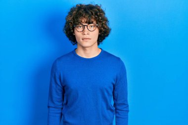 Sıradan kıyafetler ve gözlük takan yakışıklı genç adam yüzünde ciddi bir ifadeyle rahatlamış. Basit ve doğal bir şekilde kameraya bakıyorsun.. 