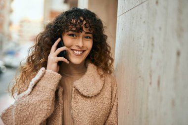 Genç İspanyol kadın gülümsüyor. Şehirdeki akıllı telefondan konuşuyor.