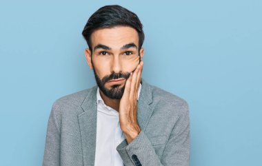 İş kıyafetleri giyen genç İspanyol adam kollarını kavuşturarak depresyondan sıkılmış ve yorgun görünüyor.. 