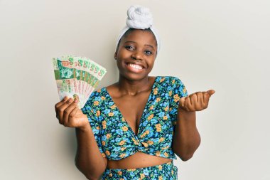 Sarıklı genç Afrikalı bir kadın elinde Hong Kong 'lu 50 dolarlık banknotlarla gururla bağırıyor, zaferi kutluyor ve başarıyı kollarını kaldırarak kutluyor. 