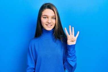 Balıkçı yaka kazak giyen genç esmer kız parmaklarıyla dört numarayı gösteriyor ve gülümsüyor. Kendinden emin ve mutlu.. 