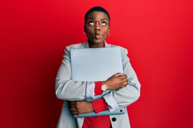 Genç Afrikalı Amerikalı iş kadını dizüstü bilgisayar tutuyor, ağzı balık gibi bakıyor, gözlerini kıstı, deli ve komik.. 