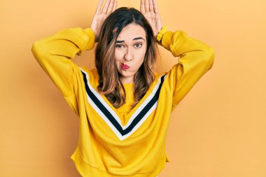 Günlük kıyafetler giyen, tavşan kulağı yapan, avuçlarıyla alaycı ve şüpheci görünen genç İspanyol kız. Paskalya tavşanı konsepti. 