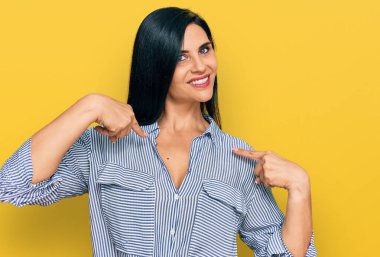 Günlük kıyafetler giyen, kendine güvenen, gülümseyen, kendini gururlu ve mutlu gösteren genç beyaz bir kadın.. 