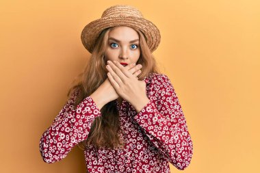 Yazlık şapka takan güzel sarışın kadın yanlışlıkla elleri ile ağzını kapatırken şok oldu. gizli kavram. 